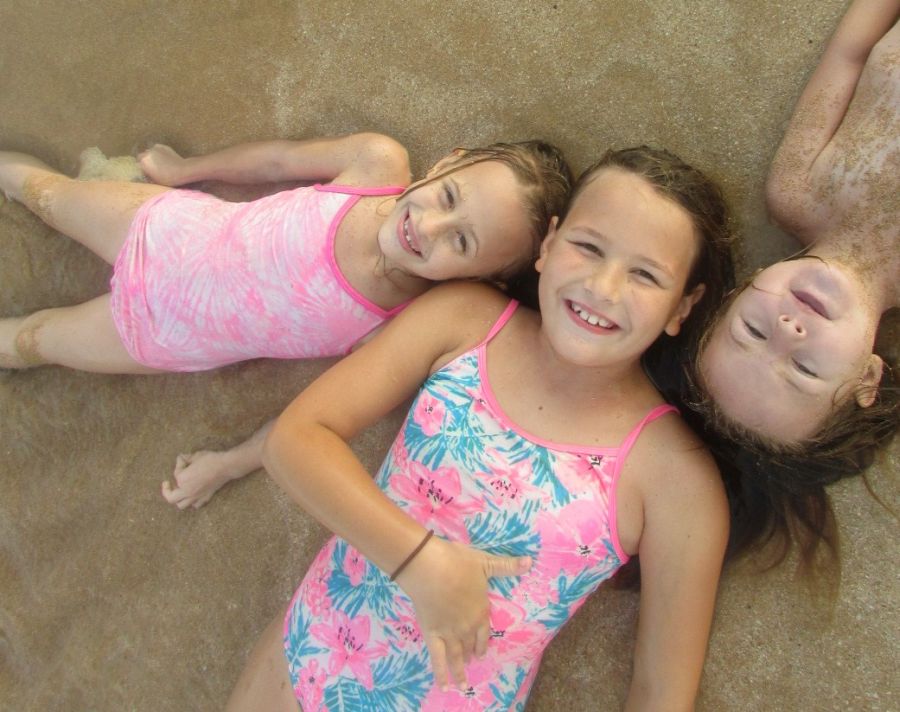 Three happy young sisters on a Molokai beach