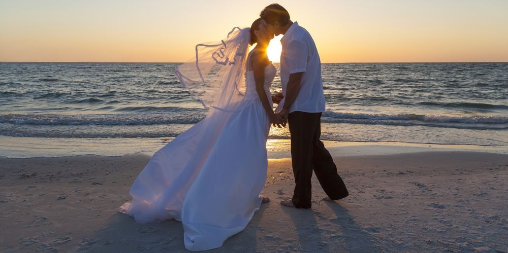 Maui wedding beach: a just-married couple is kissing at sunset on a beach in Maui