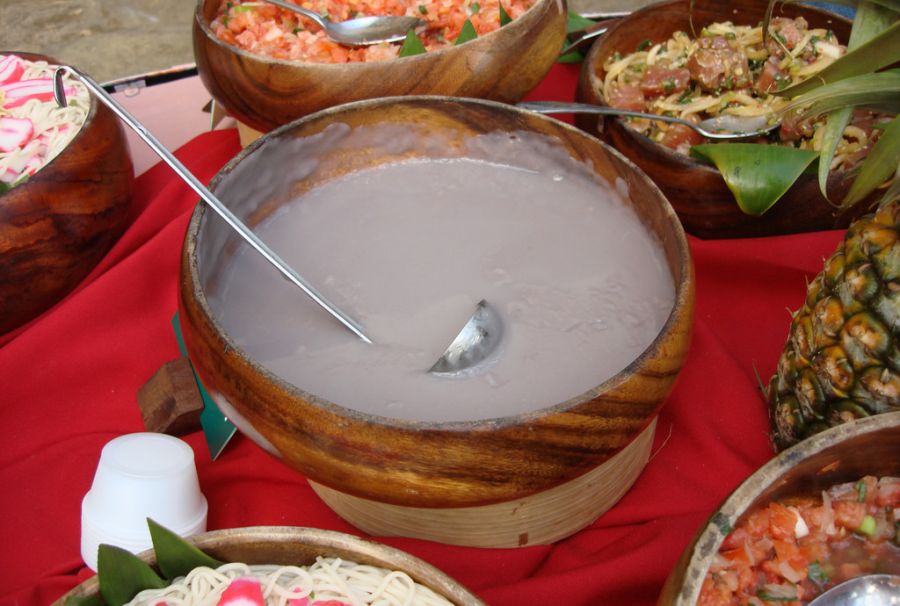 A bowl of poi in the center of the table, surrounded by other dishes; Hawaii