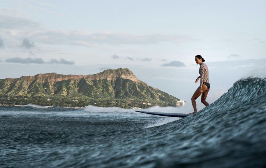 A girl on surfboard with Diamond Head in the background. Waikiki, Oahu.
