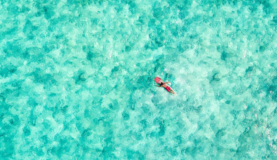 A surfer lying on his board in turquoise waters near Honolulu