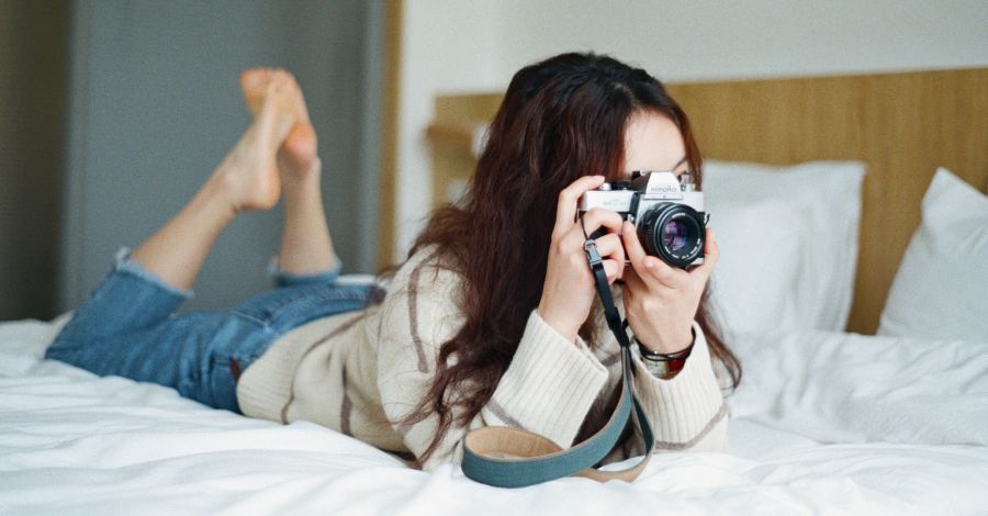 A young lady on the bed taking photos