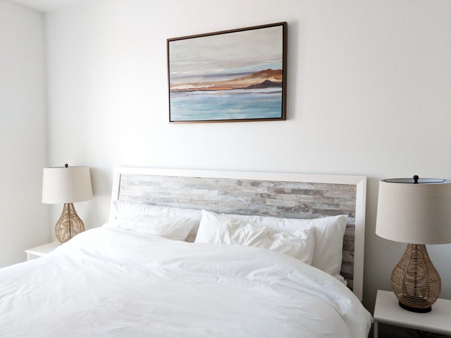 Vacation rental bedroom, full of light; modern decorations, light colors, white linens.