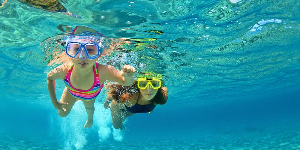 Happy family - mother with baby girl dive underwater with fun in sea pool. Healthy lifestyle, active parent, people water sport outdoor adventure, swimming lessons on beach summer holidays with child