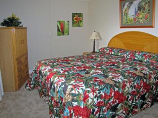 Bedroom with Cal-king bed.  Louver windows catch evening breezes and allow you to fall to sleep to the sound of the waves.